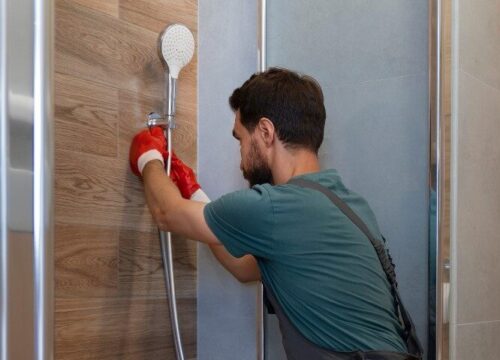 Plombier en train de réparer une installation sanitaire avec un équipement de protection individuelle, illustrant les services d'entretien et de plomberie écologiques.